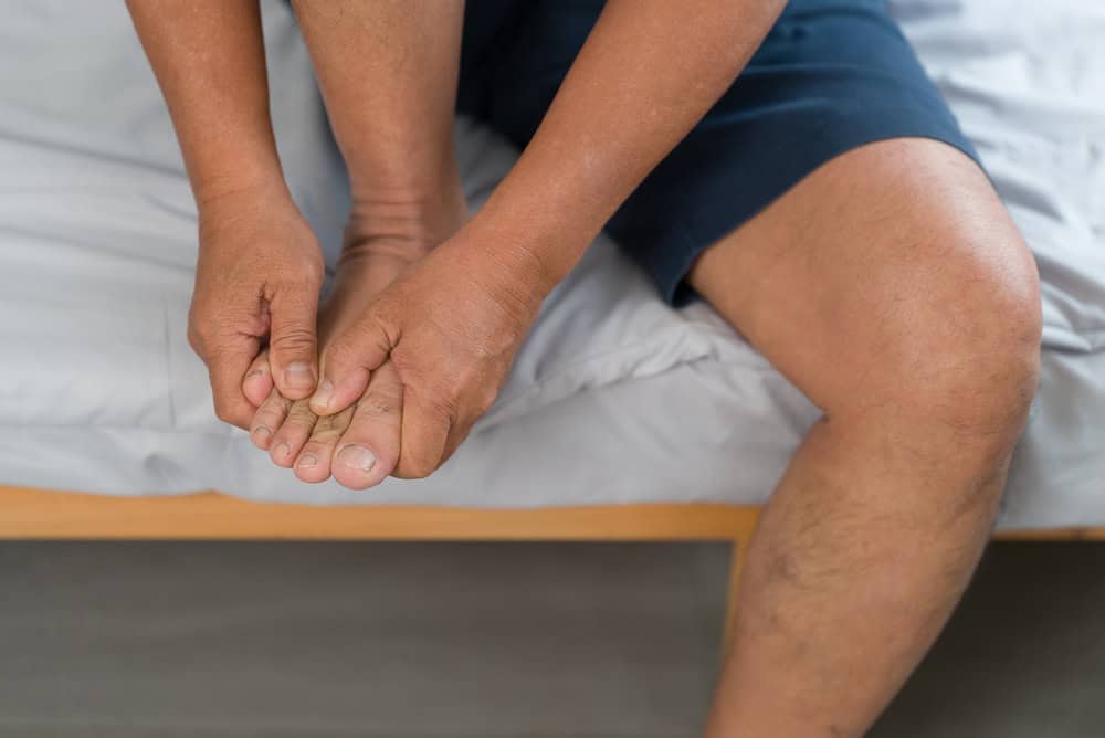 Man feeling foot numbness, a common warning sign of diabetic foot ulcers needing treatment