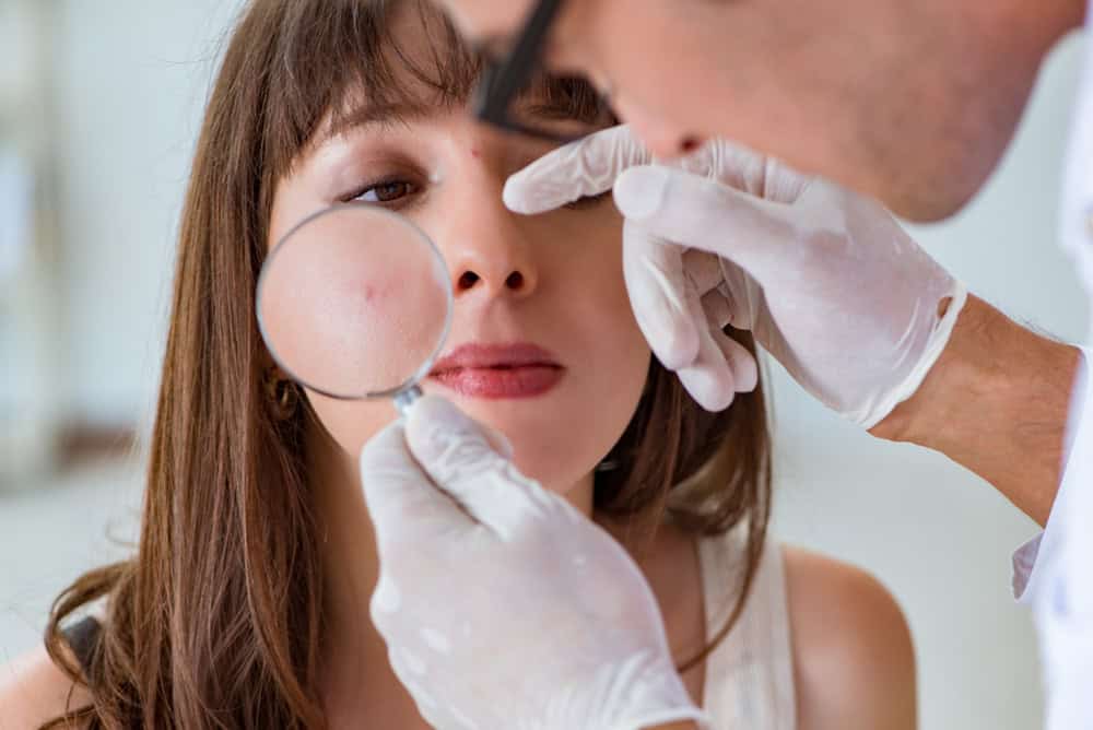 Doctor assessing acne scars on a patient's face before planning treatment