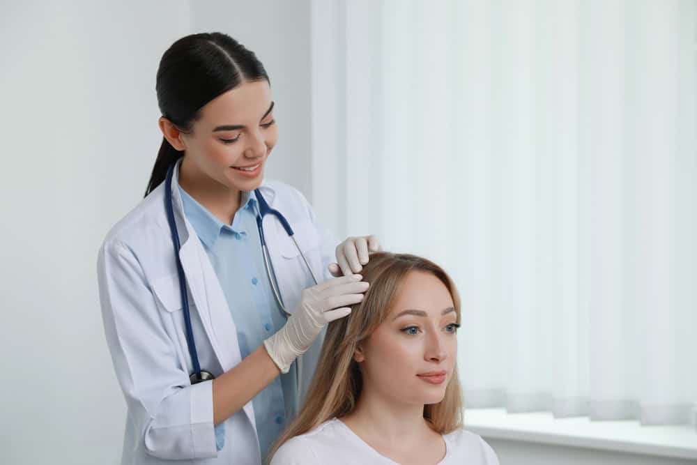 A doctor checks a patient's scalp to look for early signs of female pattern hair loss