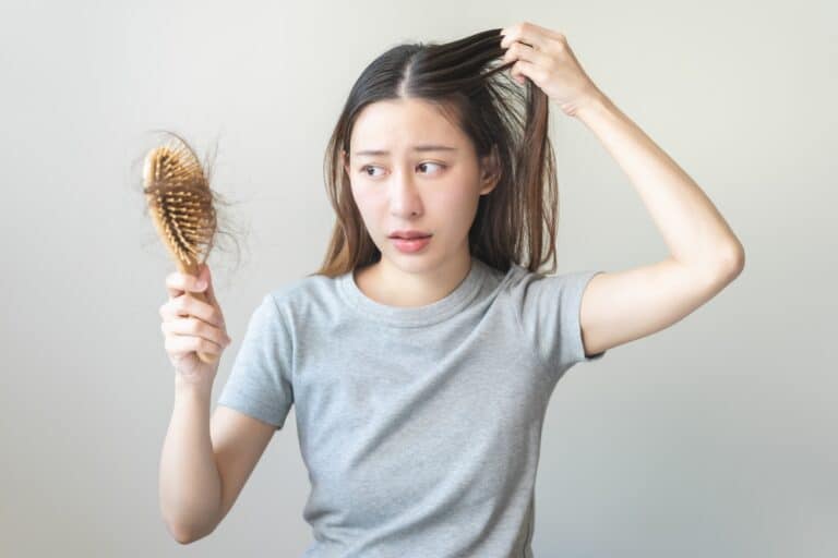 Woman noticing hair sheddings in her hairbrush, a common sign of hair loss due to Ozempic.