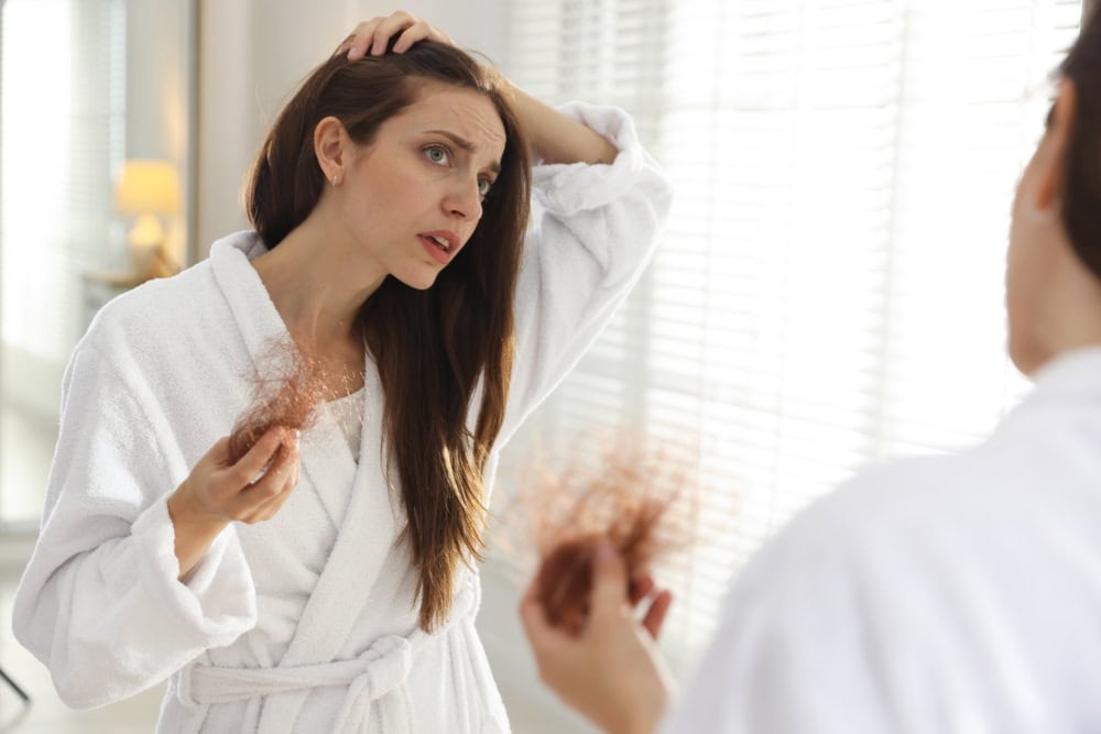 Woman noticing hair loss in the mirror