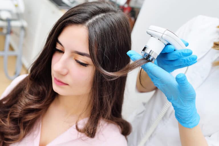 A physician performing trichoscopy on a patient before recommending stem cell hair treatment.