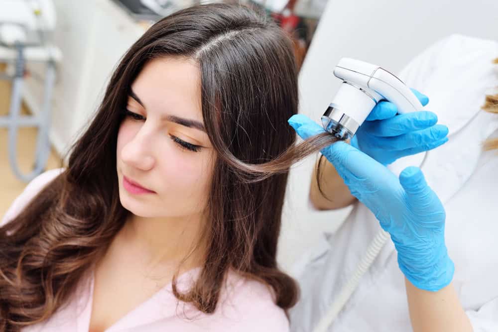 A physician performing trichoscopy on a patient before recommending stem cell hair treatment.